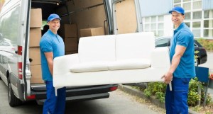 Two movers from a furniture store removing an old couch.