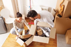 two people lifting full cardboard moving boxes off floor