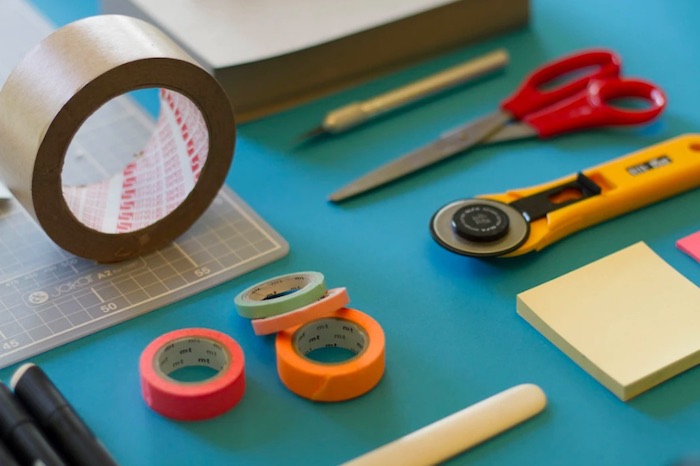 packing tape, scissors, and other materials on blue table