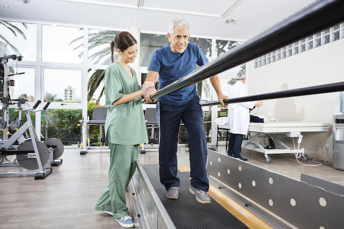 Physical therapist helps man walk