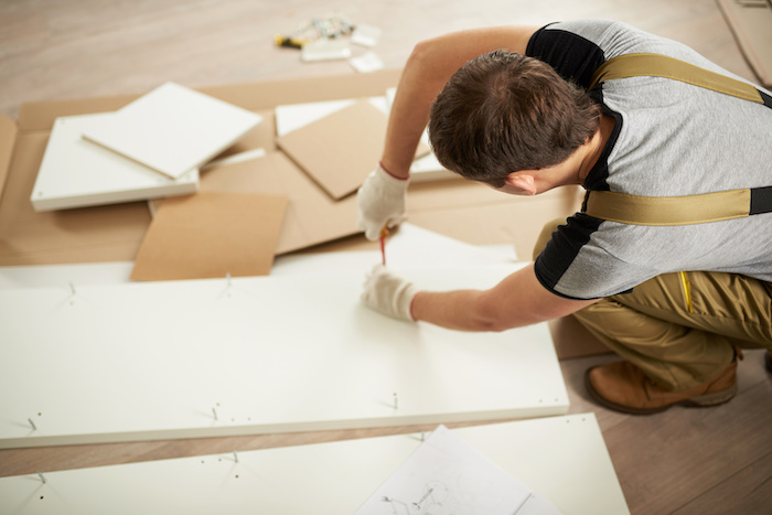 Professional carefully measuring a piece of wood for furniture assembly.