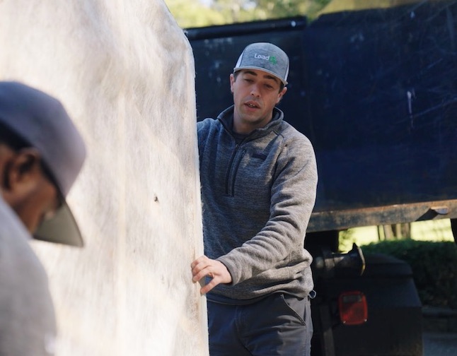 Two handymen loading a mattress into a moving truck.