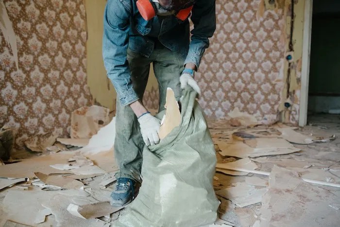 Team member loading building material waste into a bag for disposal.