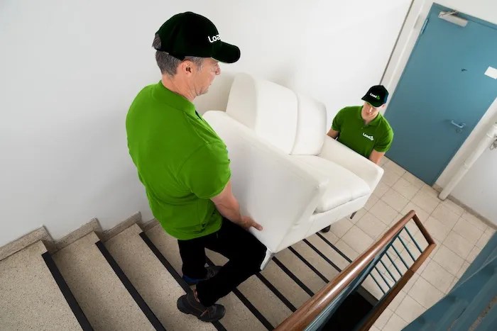 Two Loaders removing a junk couch from a seniors home.