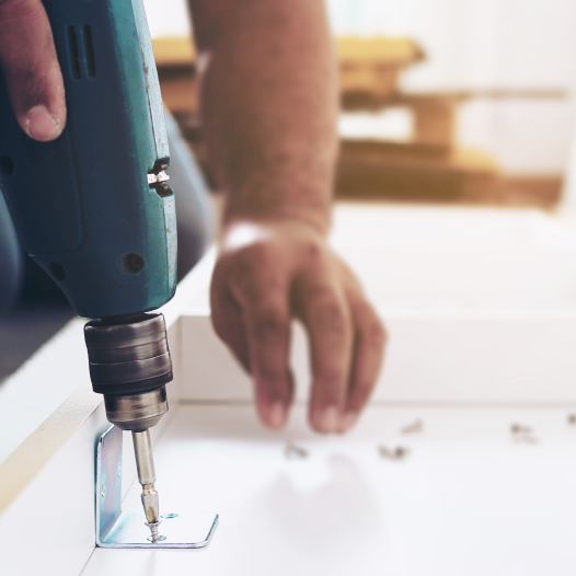 Professional with power tool putting together futon pieces