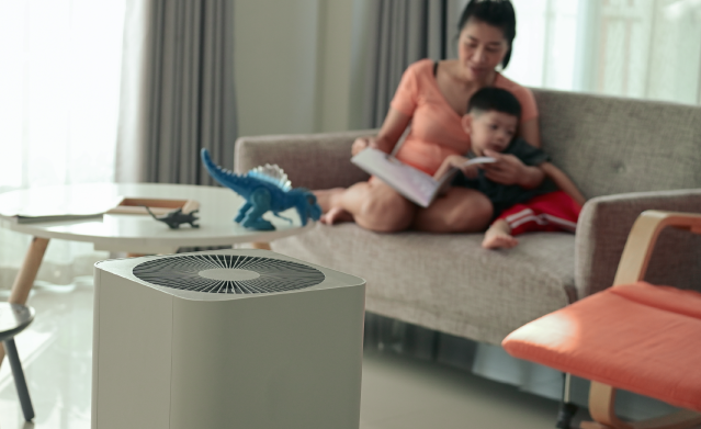 Mom and child sitting on couch with air purifier in the room