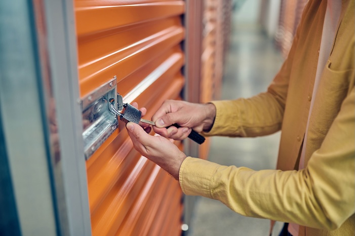 Storage unit employee putting a metal key into the padlock hole 